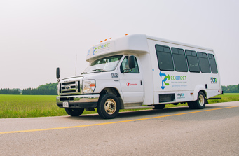 A white PC Connect bus driving down a rural road